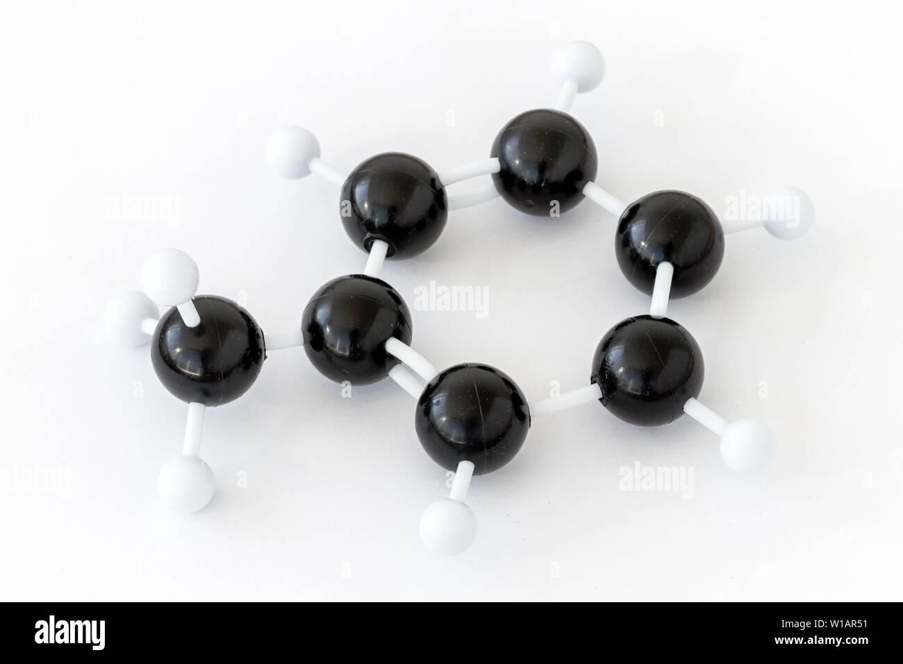 Plastic ball-and-stick model of a toluene or methylbenzene molecule (C7H8), shown with kekule structure on a white background. Methyl group left. Stock Photo