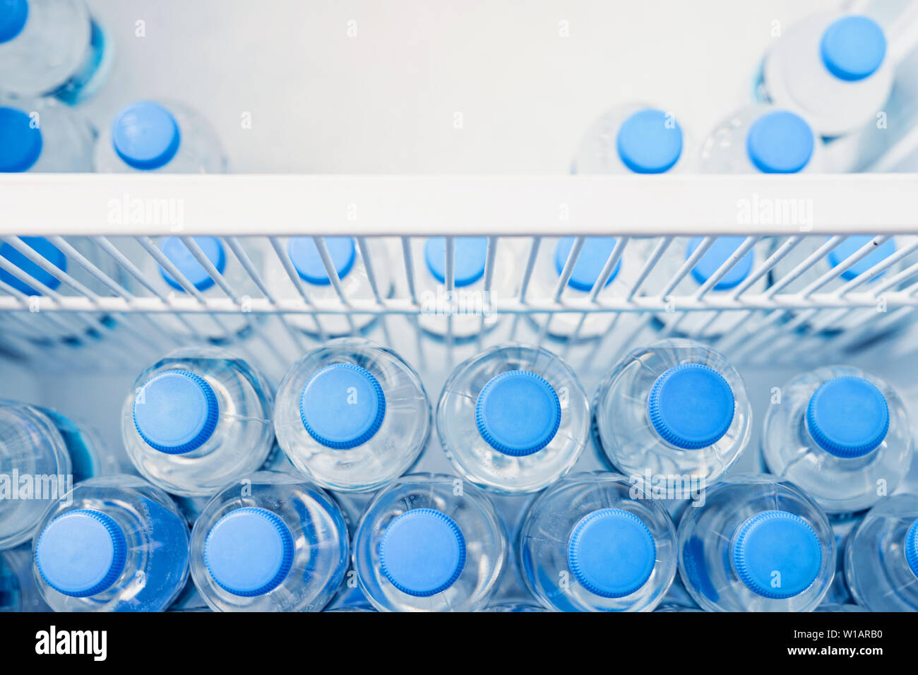 Rows of many transparent plastic bottles with drinking water supply in  white refrigerator. Mineral water stack storage in fridge to drink on hot  Stock Photo - Alamy