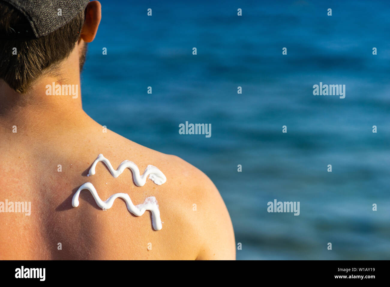 Young Man With Wave Formed Suncream On His Shoulder Standing At The Beach Looking Over The Sea Stock Photo Alamy