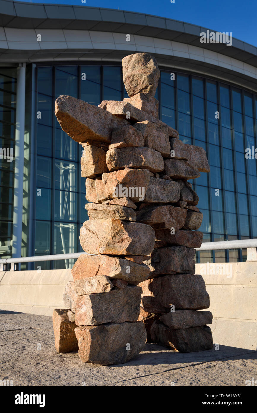 Inukshuk Inuit red stone statue of man with raised arms at Pearson International Airport Terminal 1 Toronto Canada in morning sunrise Stock Photo