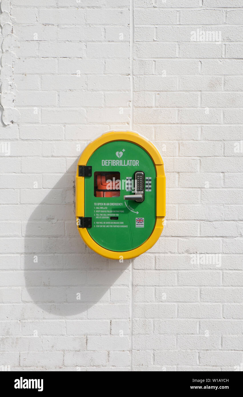 Life saving Defibrillator equipment positioned on wall of building in sports area of local park Blackpool lancashire England UK Stock Photo