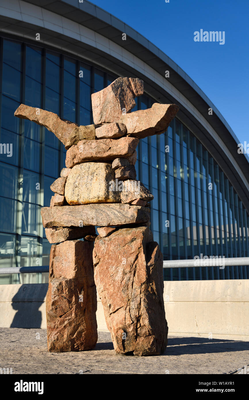 Inukshuk red stone statue with outstretched welcoming arms at Pearson International Airport Terminal 1 Toronto Canada in morning sunrise Stock Photo