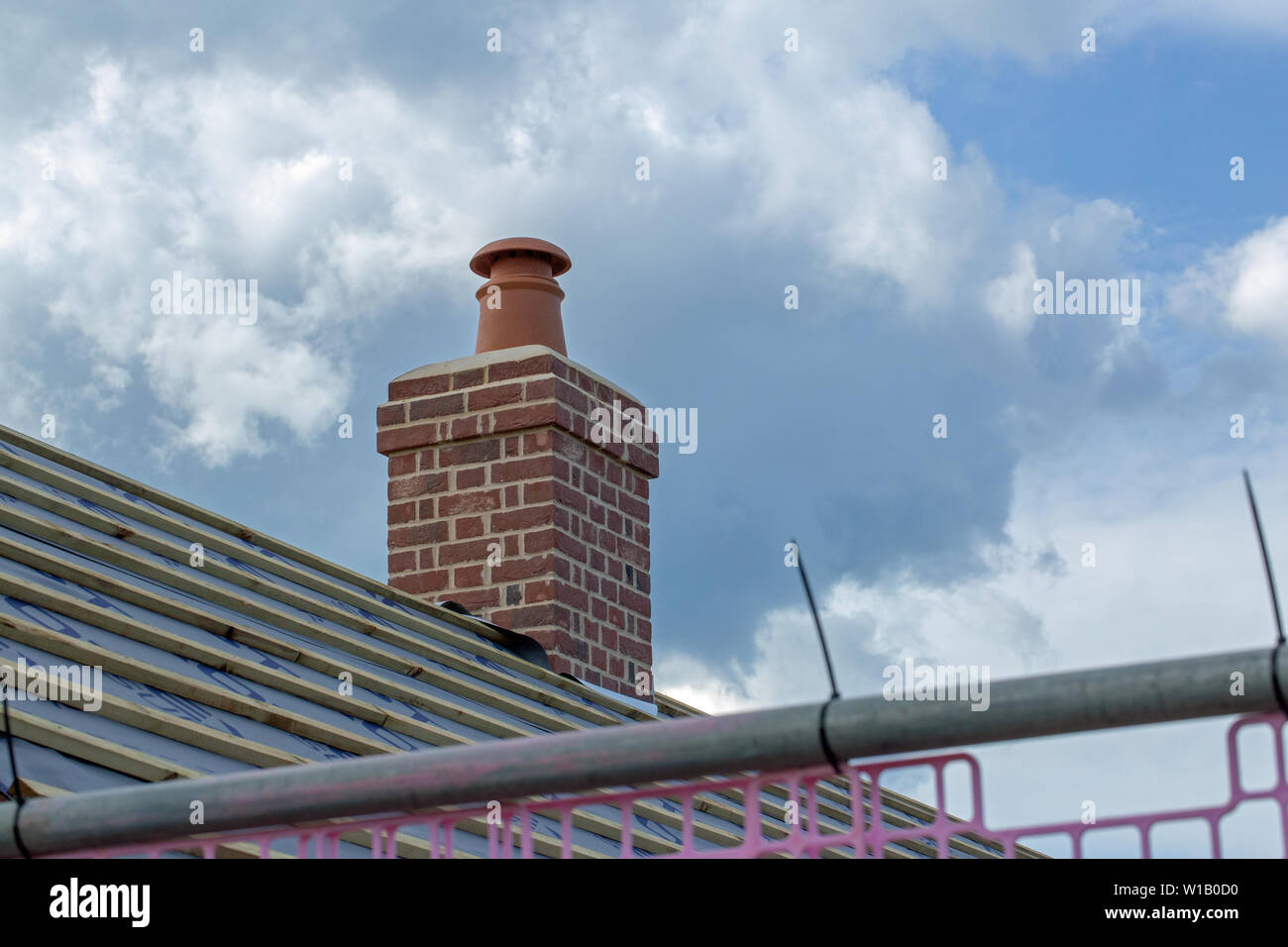 Chimney Pot, Chimney Stack above a new roof, on a re-build, redundant farm building, conversion. Long and short brickwork. Tiles still to be placed on the roof. Stock Photo