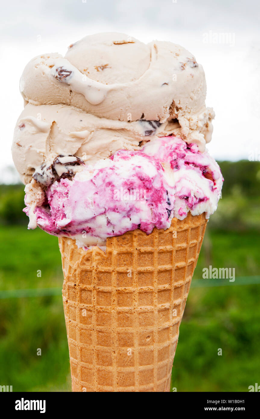 Two scoop double decker ice cream cone containing flavours of Rum and  raisin and Strawberry ripple Stock Photo - Alamy