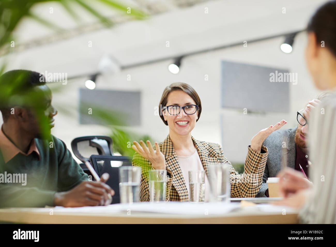 Portrait of cheerful businesswoman wearing glasses gesturing actively during meeting in office, copy space Stock Photo