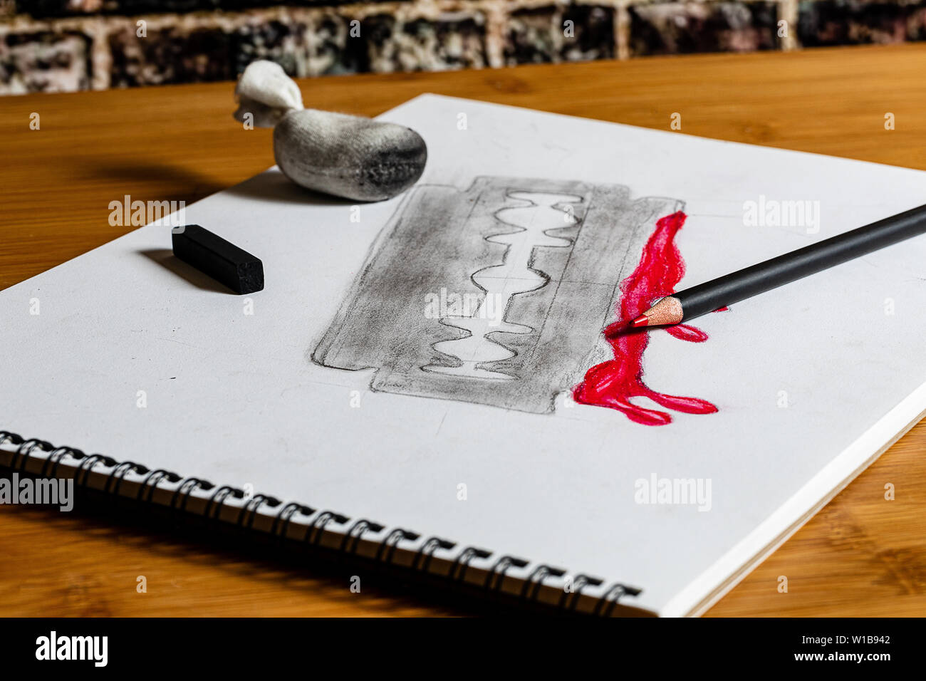 Sketch of a Bloody Razor in Charcoals and red colored pencil in an artist's sketchbook on a work table in an artist's studio.  Horror and Halloween ar Stock Photo