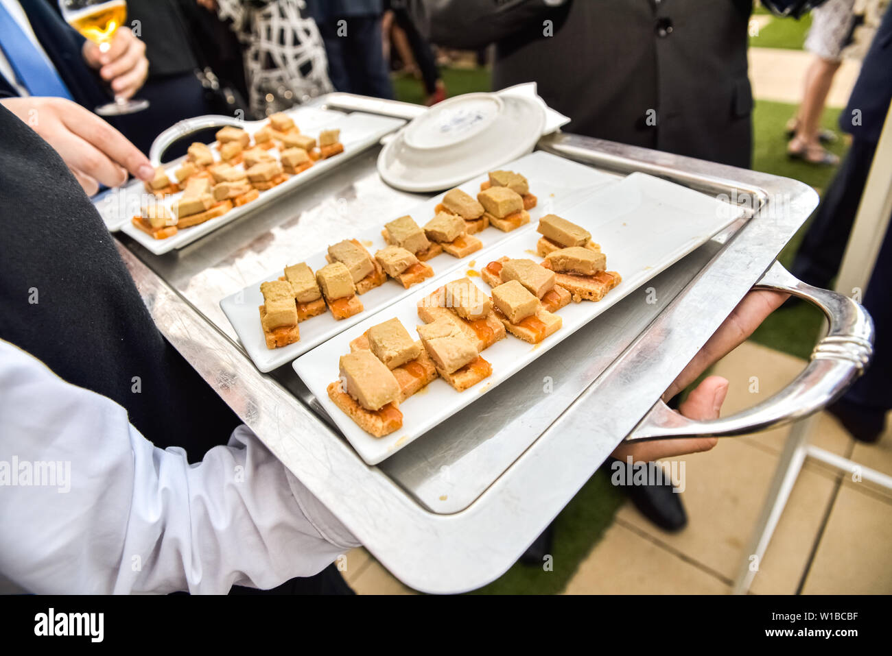 Waiters serving in trays, snacks and tapas to the guests at a business dinner. Stock Photo