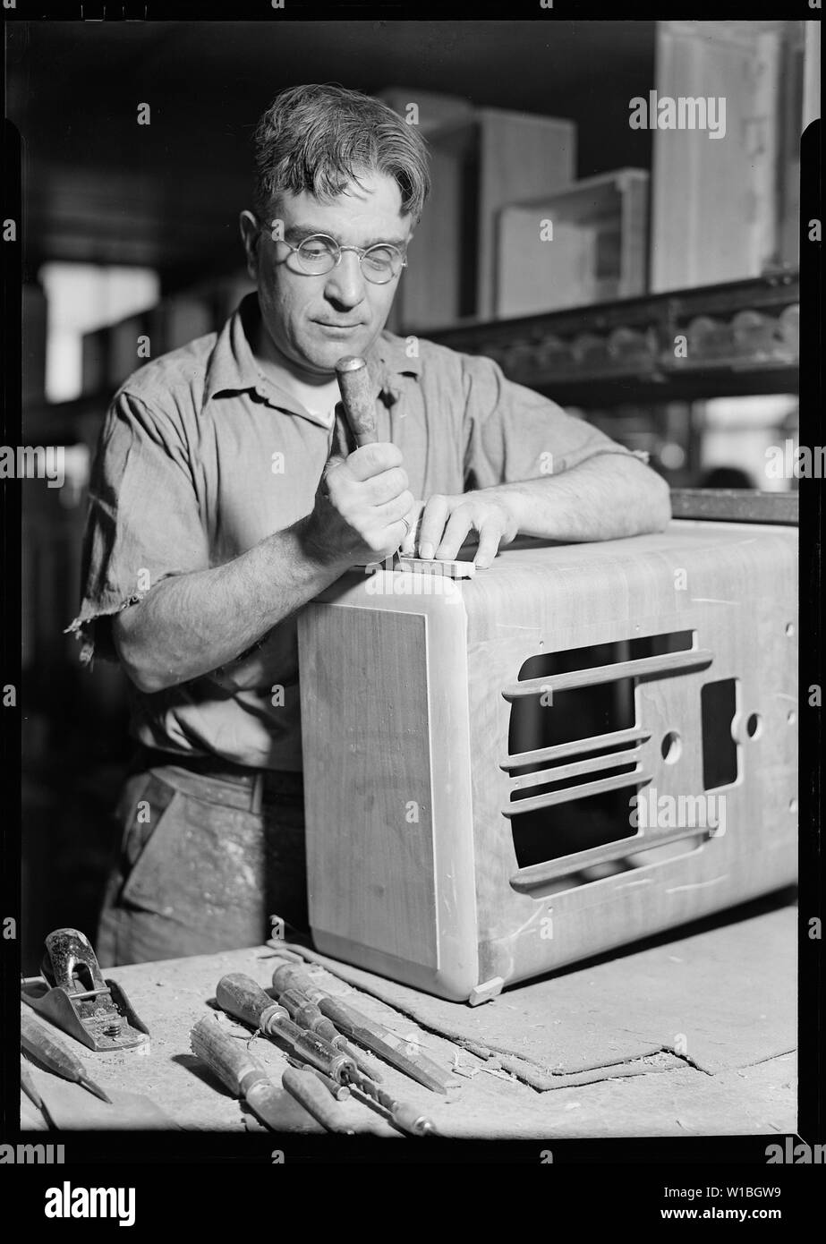 Camden, New Jersey - Cabinet making. RCA Victor. Cabinet repair man preparing to cut a piece of veneer - to replace a section of veneer damaged during the assembly of the cabinet. This is all hand work and the worker must be a skilled, experiences cabinet-maker. Stock Photo