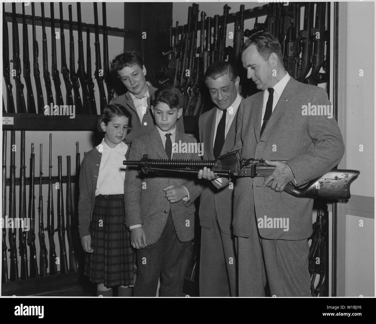 Carl Mydans, who is on the photographic staff of Life magazine, visited FBI Headquarters with his family and was conducted on a tour by Special Agent Donald G. Hanning. Mr. Mydans, his wife and Special Agent Hanning were prisoners of war of the Japanese in the Philippines and renewed their acquaintanceship and viewed a Japanese machine gun in the Firearms Section of the FBI Laboratory. Shown left to right are: Misty Mydans, Mrs. Mydans, Seth Mydans, Mr. Mydans, and Special Agent Hanning. Stock Photo