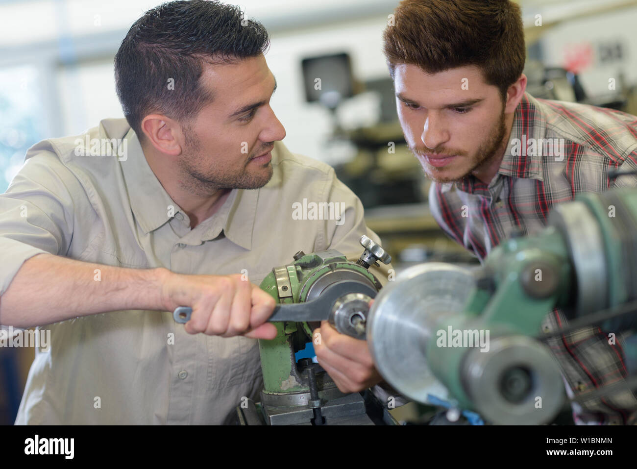 engineer teaching apprentices using metal processing machines Stock Photo