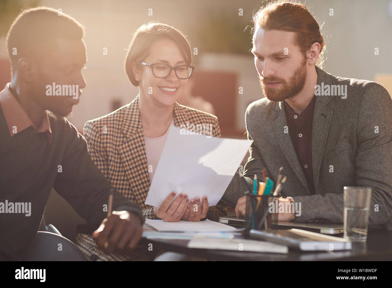 Warm toned portrait of group of business people working in cafe lit by sunlight Stock Photo