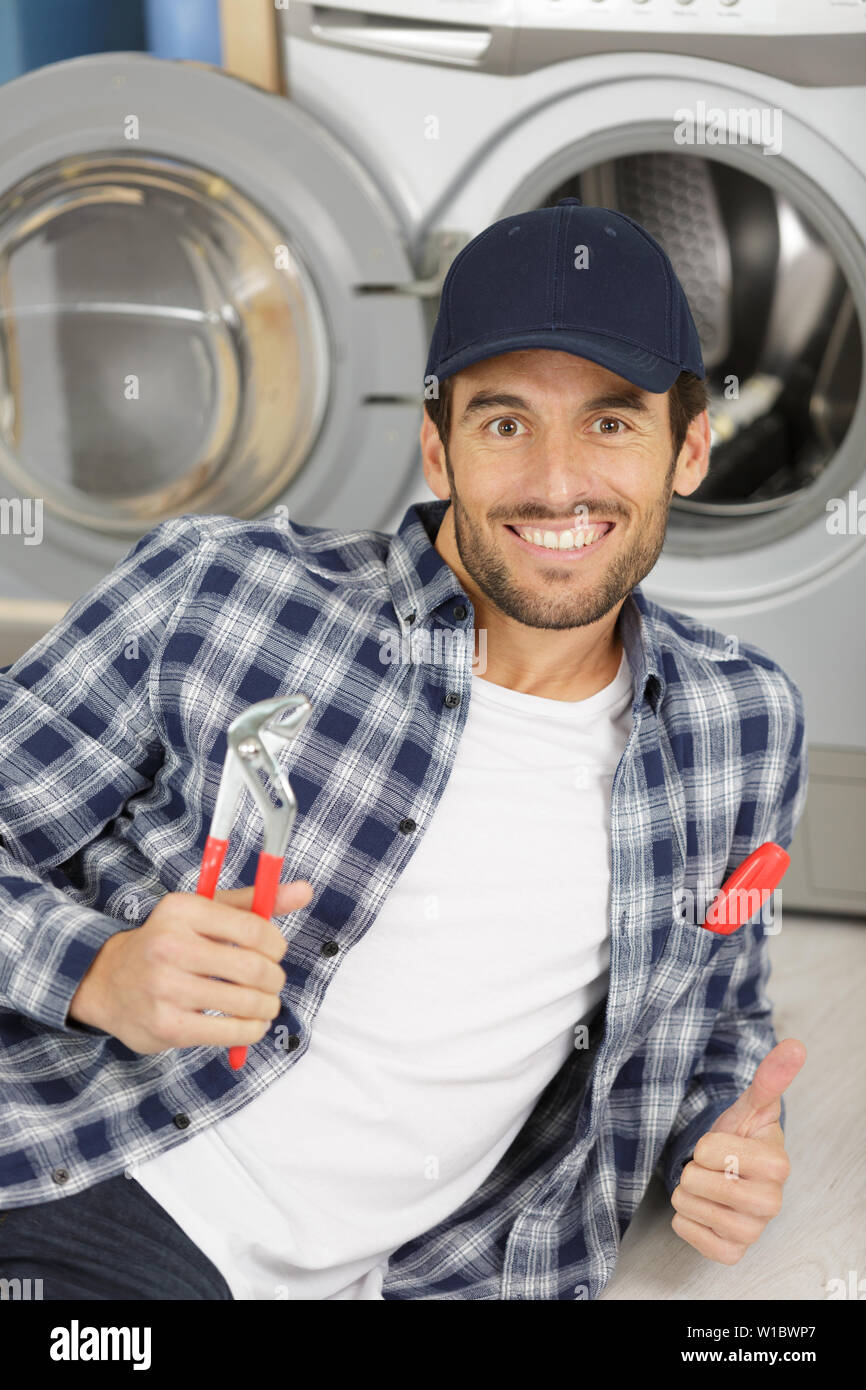 repairman repairing washing machine in the kitchen Stock Photo Alamy