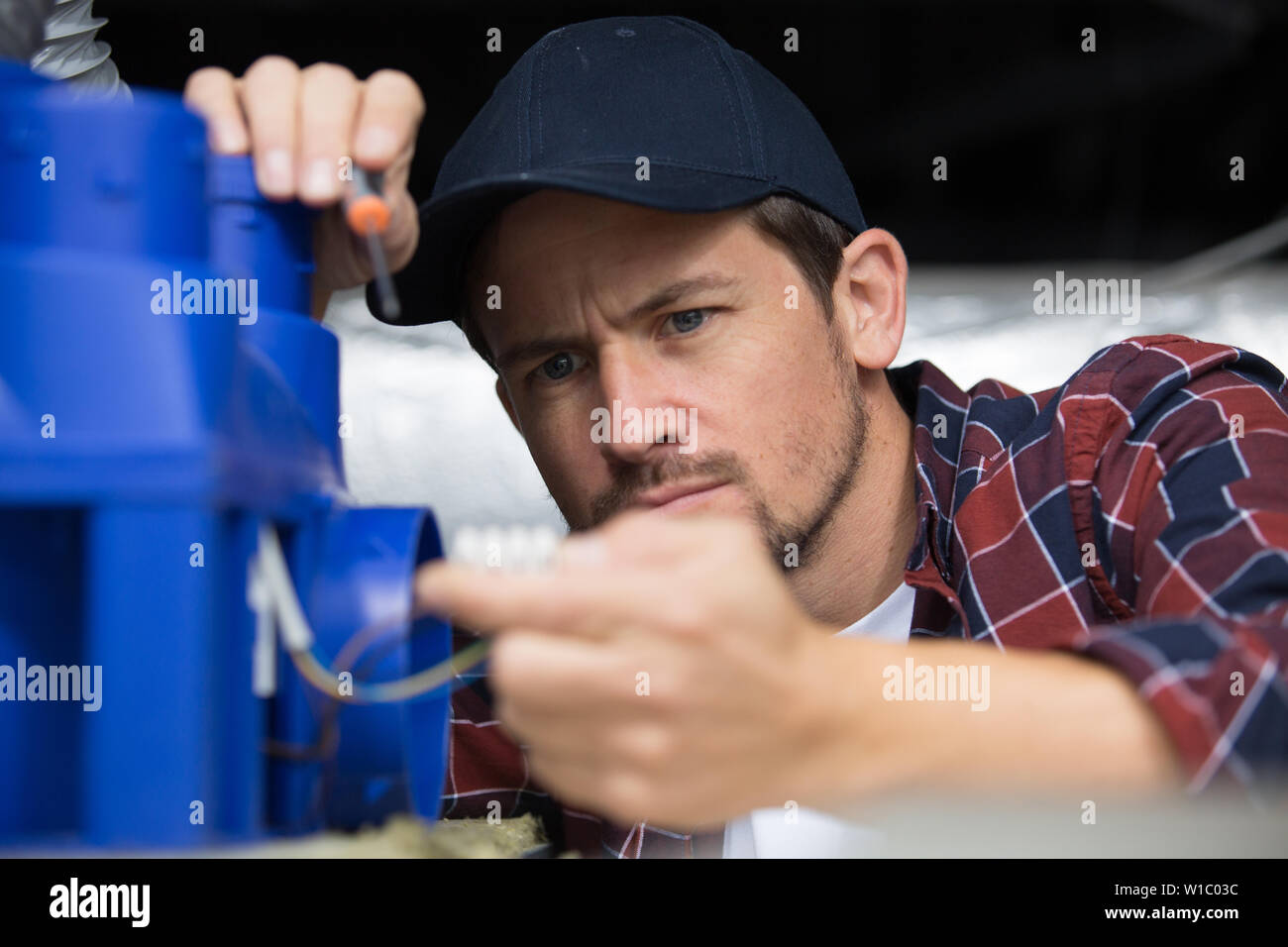 man with a screwdriver during ceilling ventilation Stock Photo