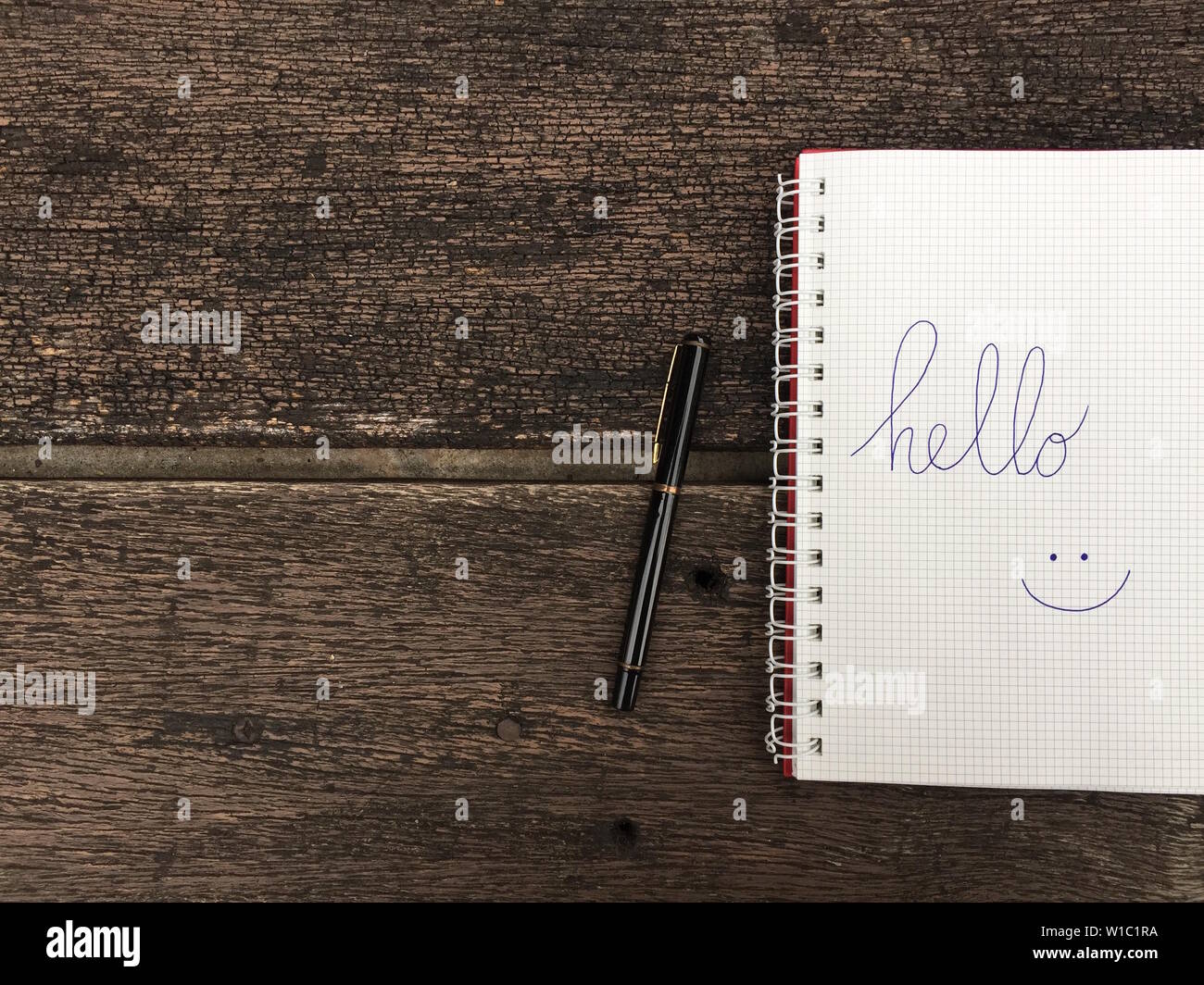 Hello text on notebook. Blank open notepad and black pen on old wood ...