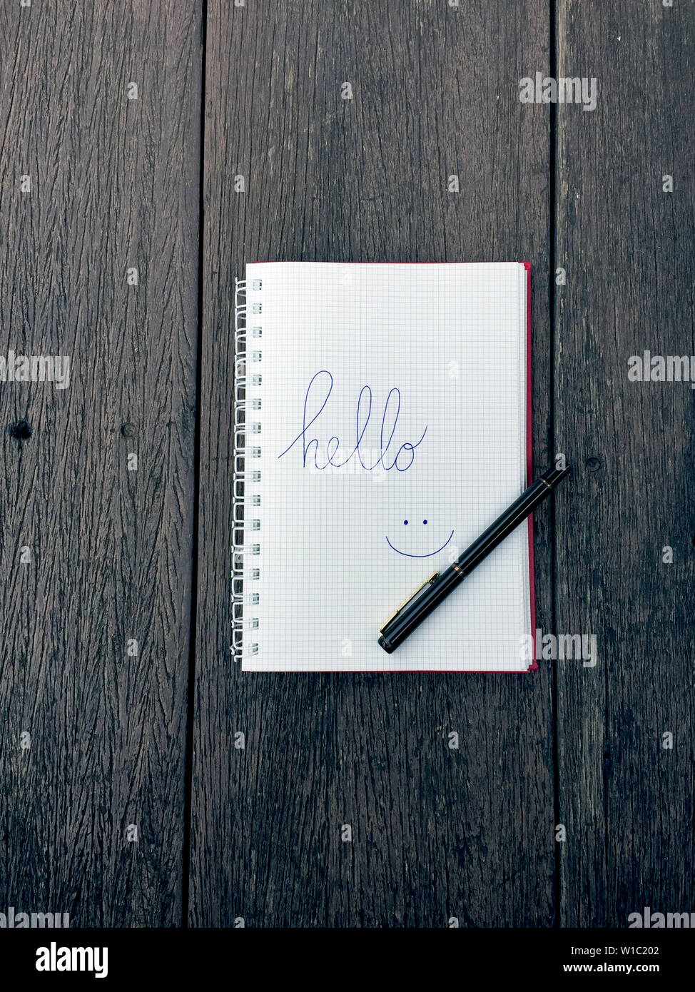 Hello text on notebook. Blank open notepad and black pen on old wood ...
