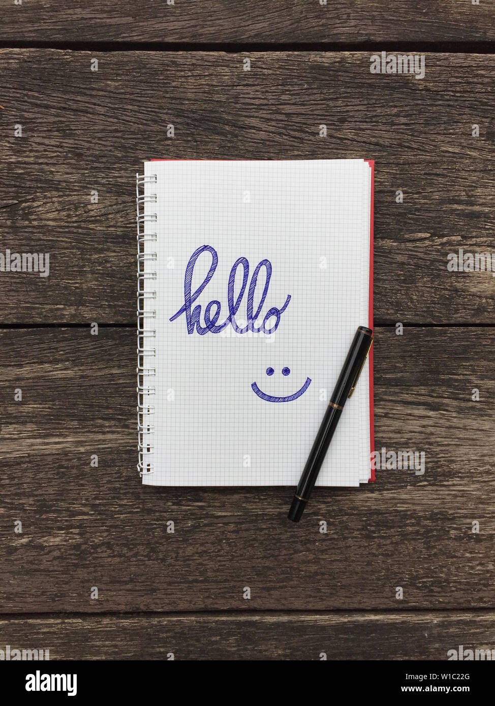 Hello text on notebook. Blank open notepad and black pen on old wood ...