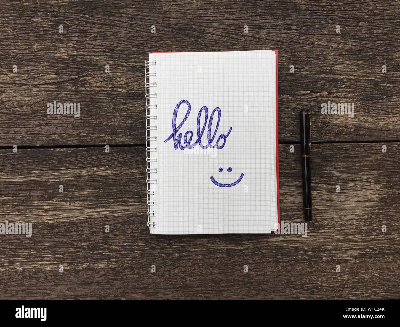 Hello text on notebook. Blank open notepad and black pen on old wood ...