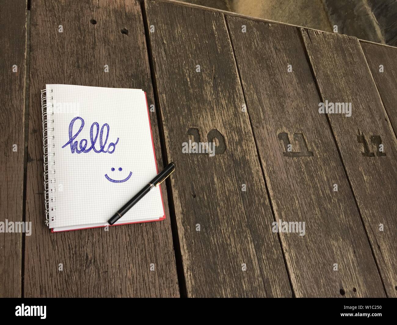 Hello text on notebook. Blank open notepad and black pen on old wood ...