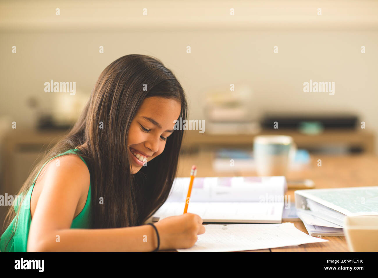 Young Girl Sitting At A Desk And Working On Her Homework Stock Photo