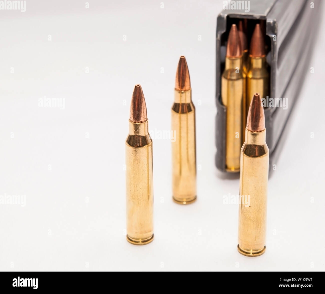 223 caliber bullets along with a loaded 223 caliber rifle magazine on a white background Stock Photo