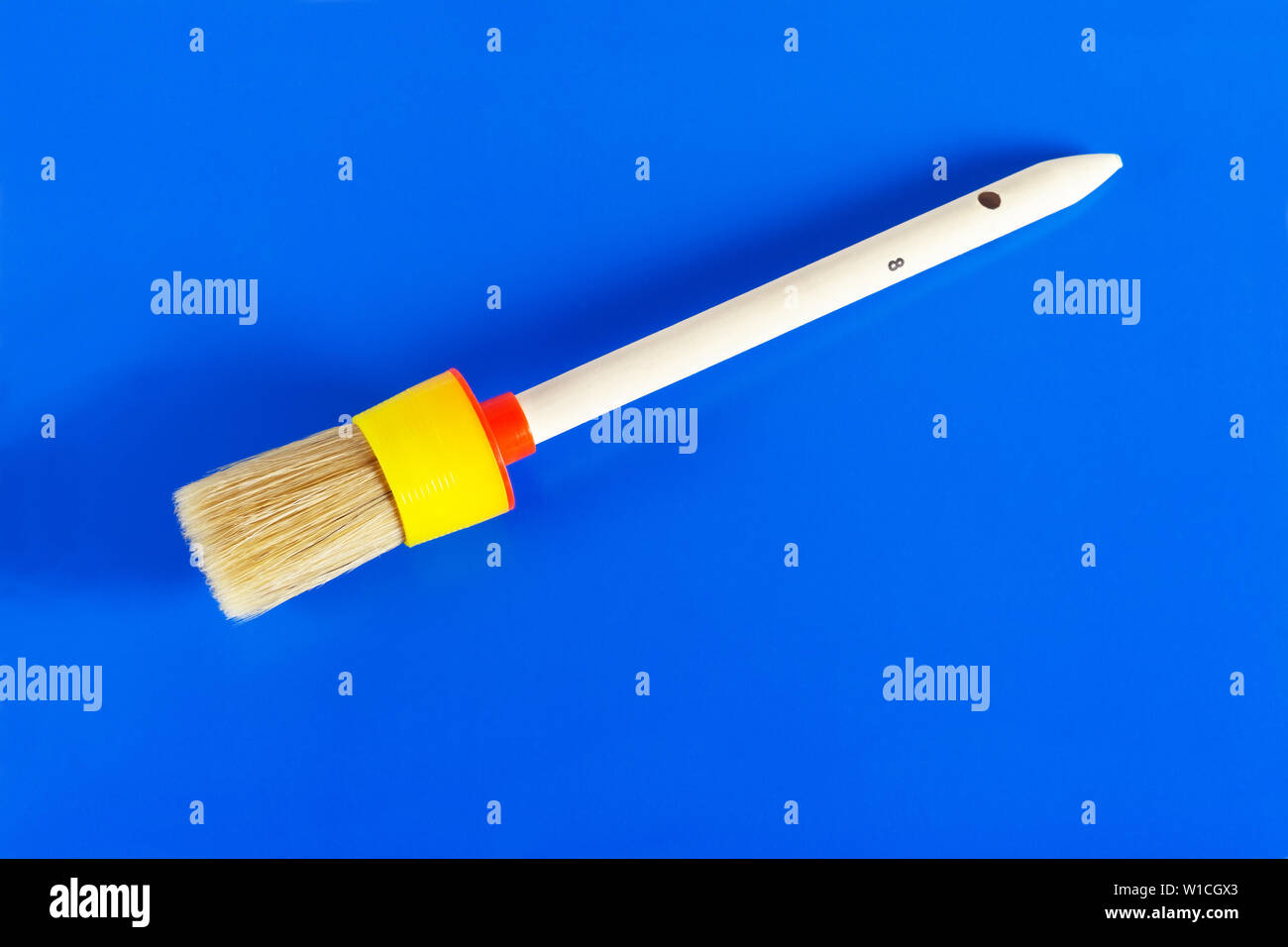 Round paint brush. Close-up on a blue background. Stock Photo