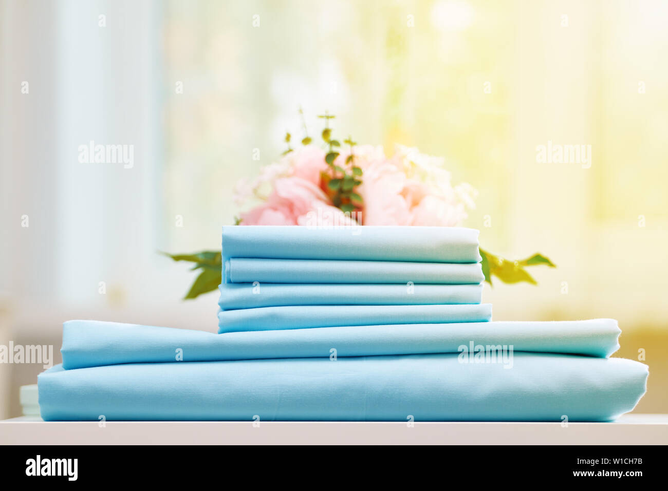 Closeup stack of blue clean bedding on the table. Blurred background. Stock Photo