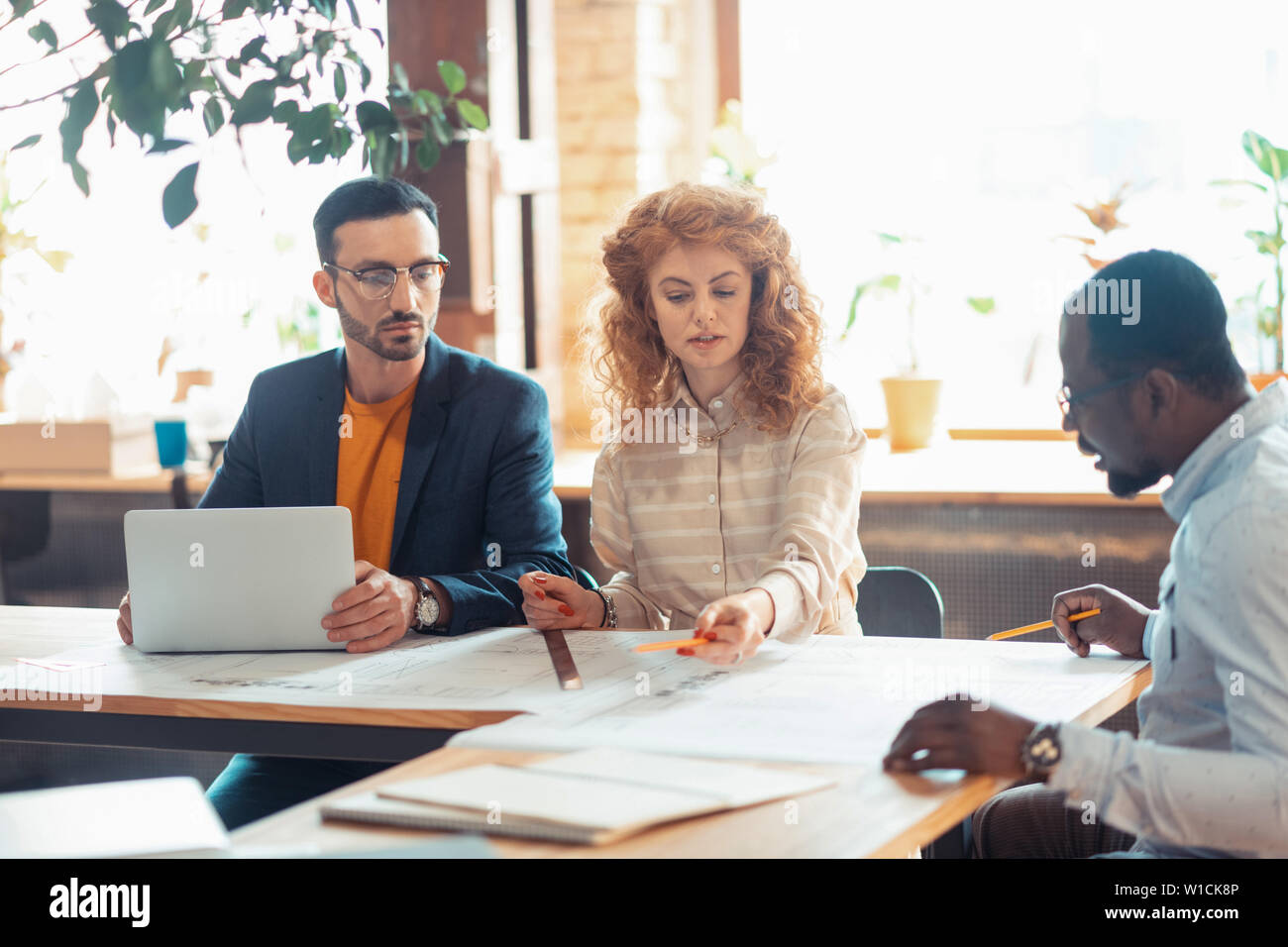 Speaking to boss. Two experienced interior designers speaking about new project to boss Stock Photo