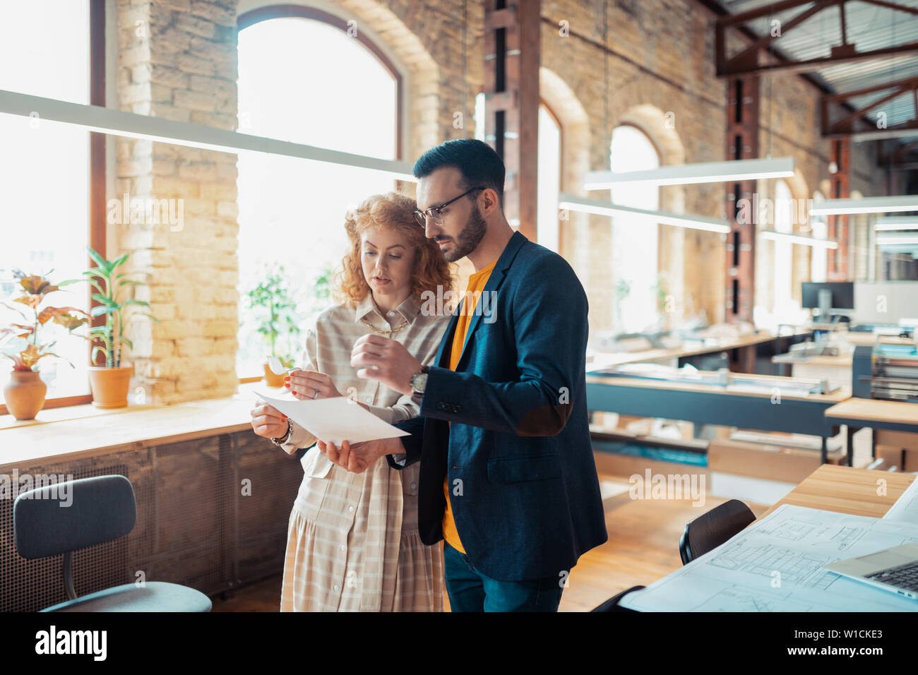 Boss assisting. Handsome bearded boss assisting his interior designer while making sketches Stock Photo