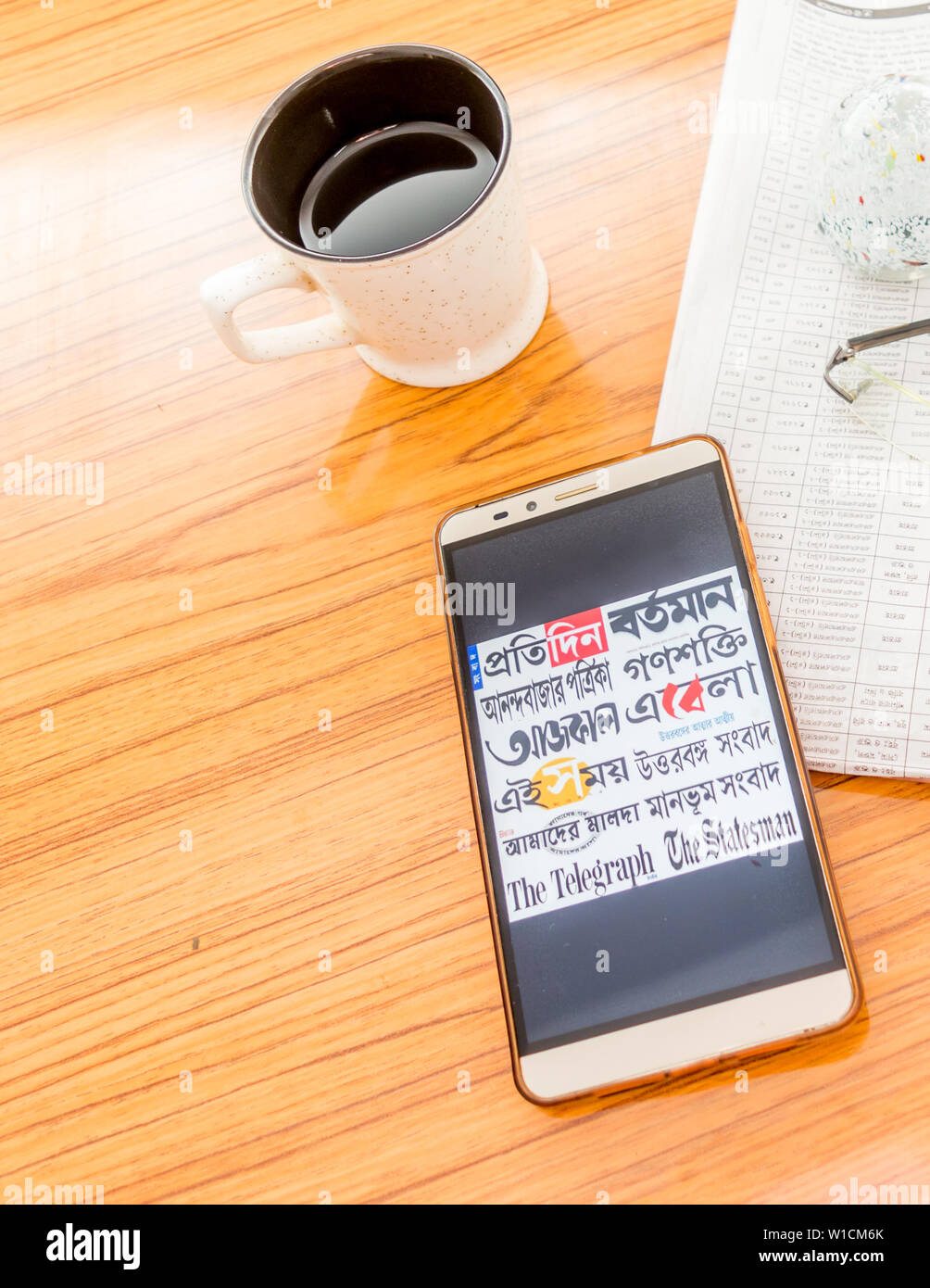 Kolkata, India, February 3, 2019: All bengali newspapers at once visible on mobile phone screen beautifully placed over a wooden table with a newspape Stock Photo