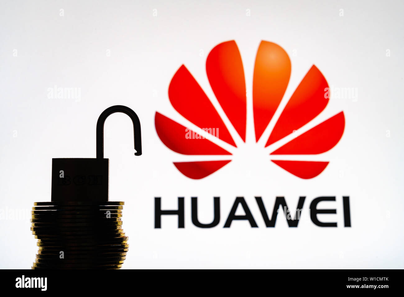 Huawei logo in background with silhouette of a unlock padlock and a key Stock Photo