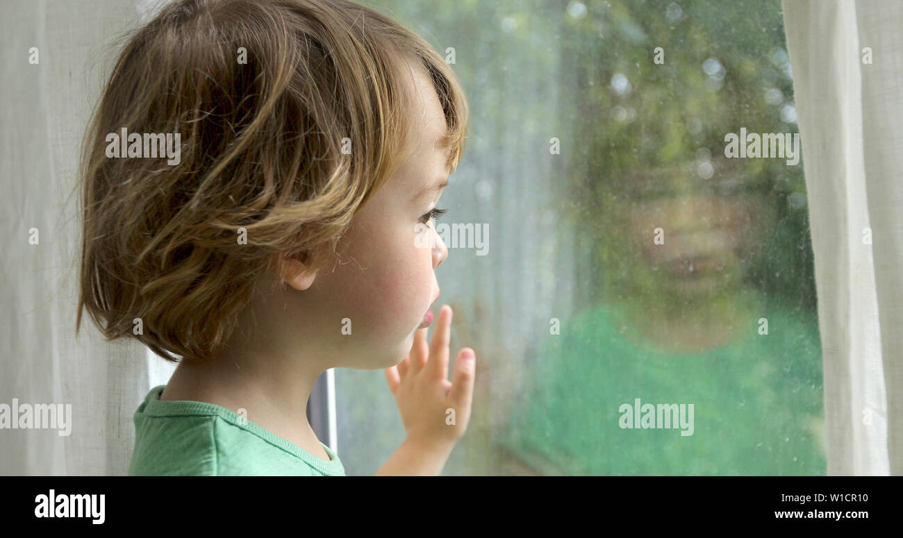 Boy is standing and looking out the window Stock Photo
