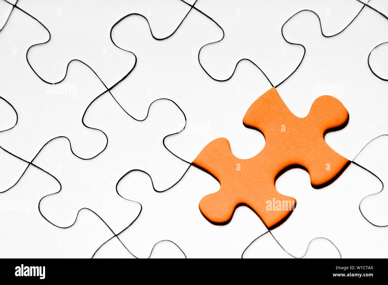 Orange puzzle piece in between of white puzzle pieces, business concept