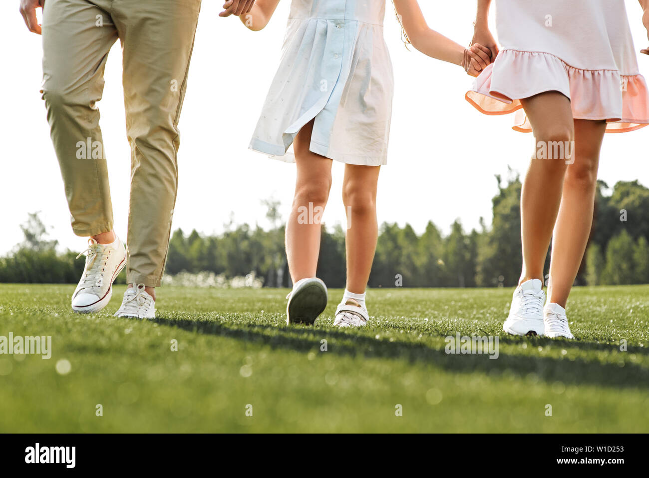 Family day. Cropped photo of happy young family of three holding hands and walking outdoors. Concept of a happy family. Picnic. Weekend Stock Photo