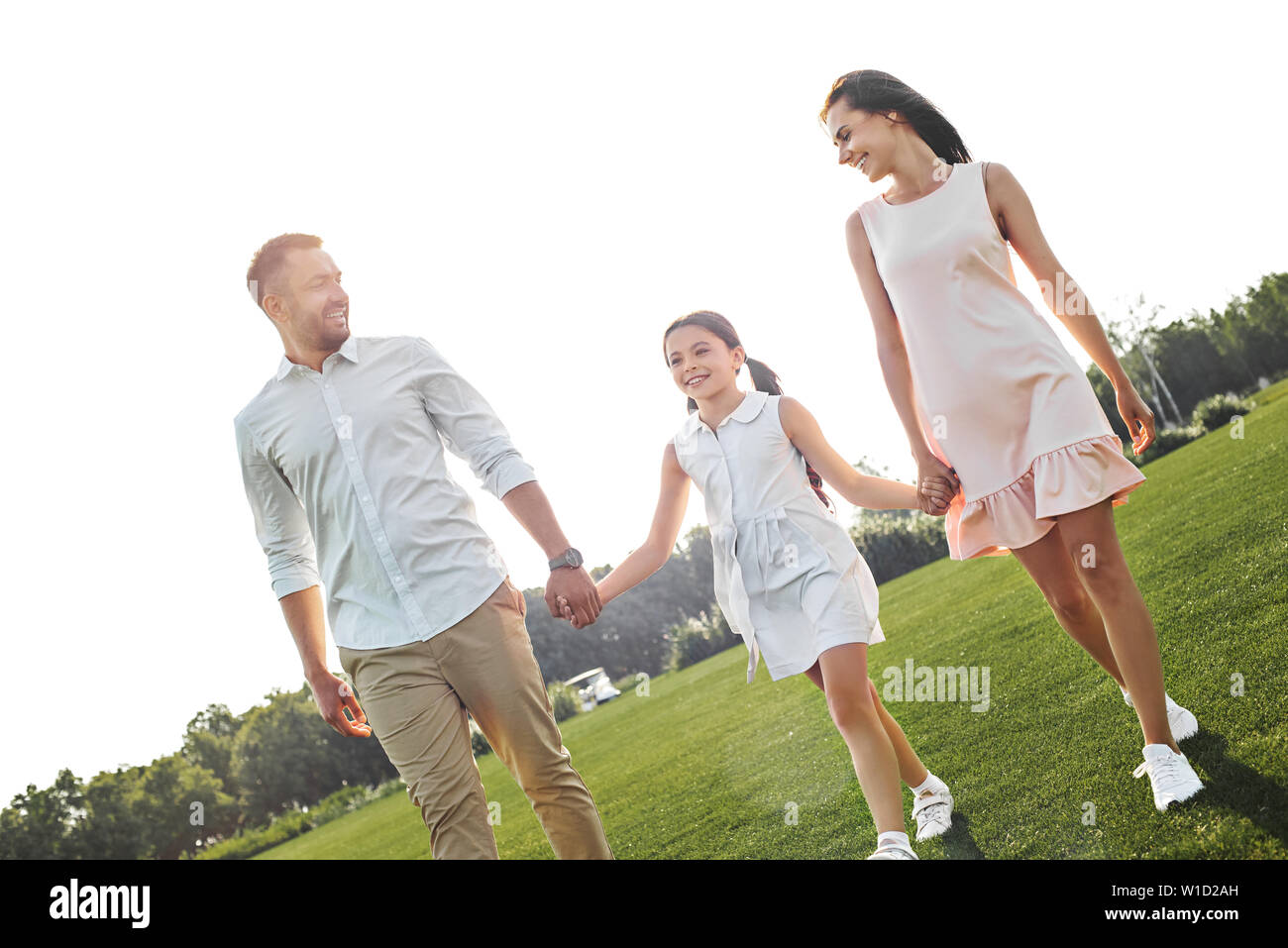 Always happy together. Full length of little happy girl walking with her parents in the park and smiling. Family concept Stock Photo