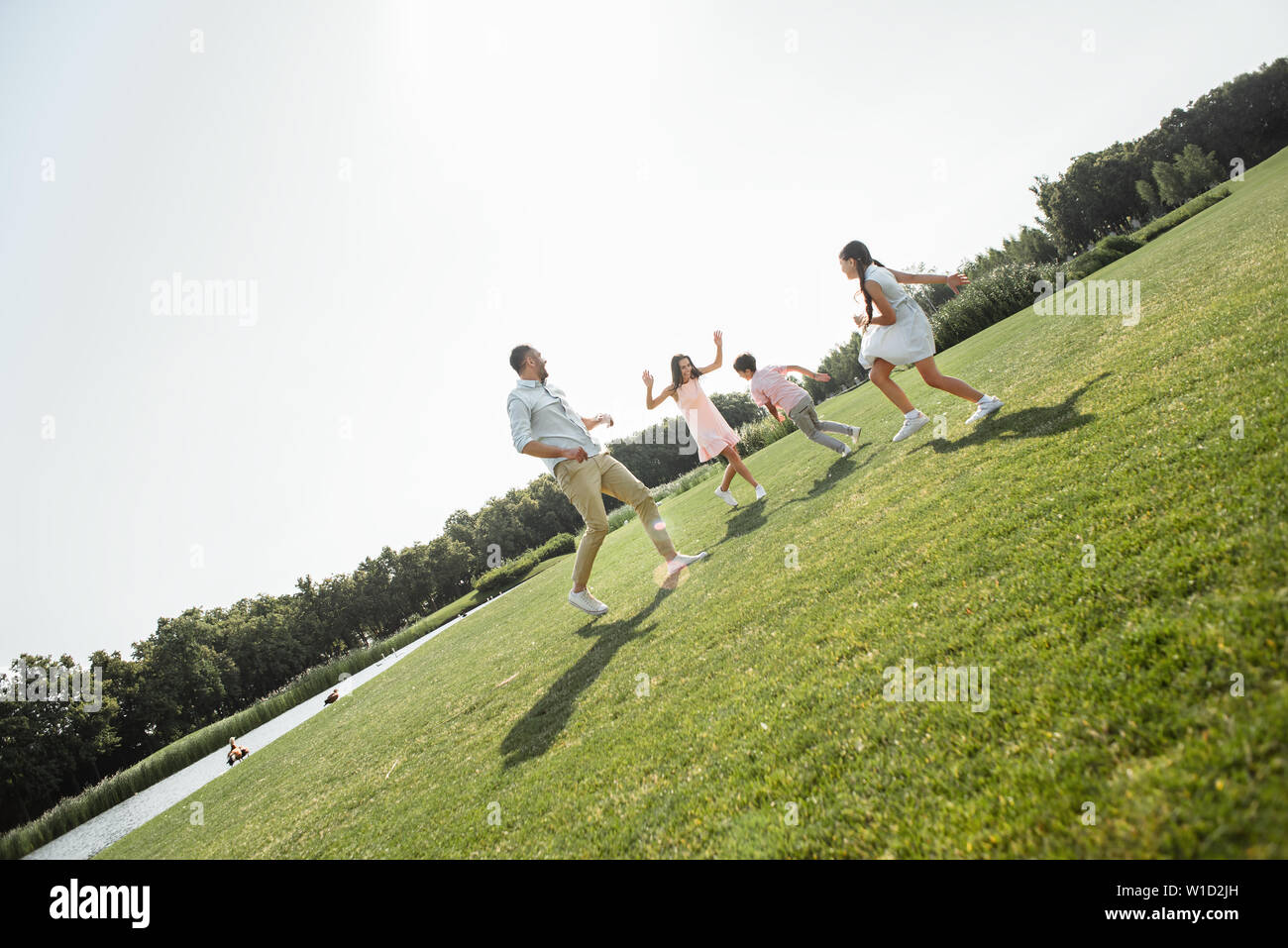 We love playing together Active and happy young family playing and smiling while spending free time outdoors in park. Picnic. Weekend Stock Photo