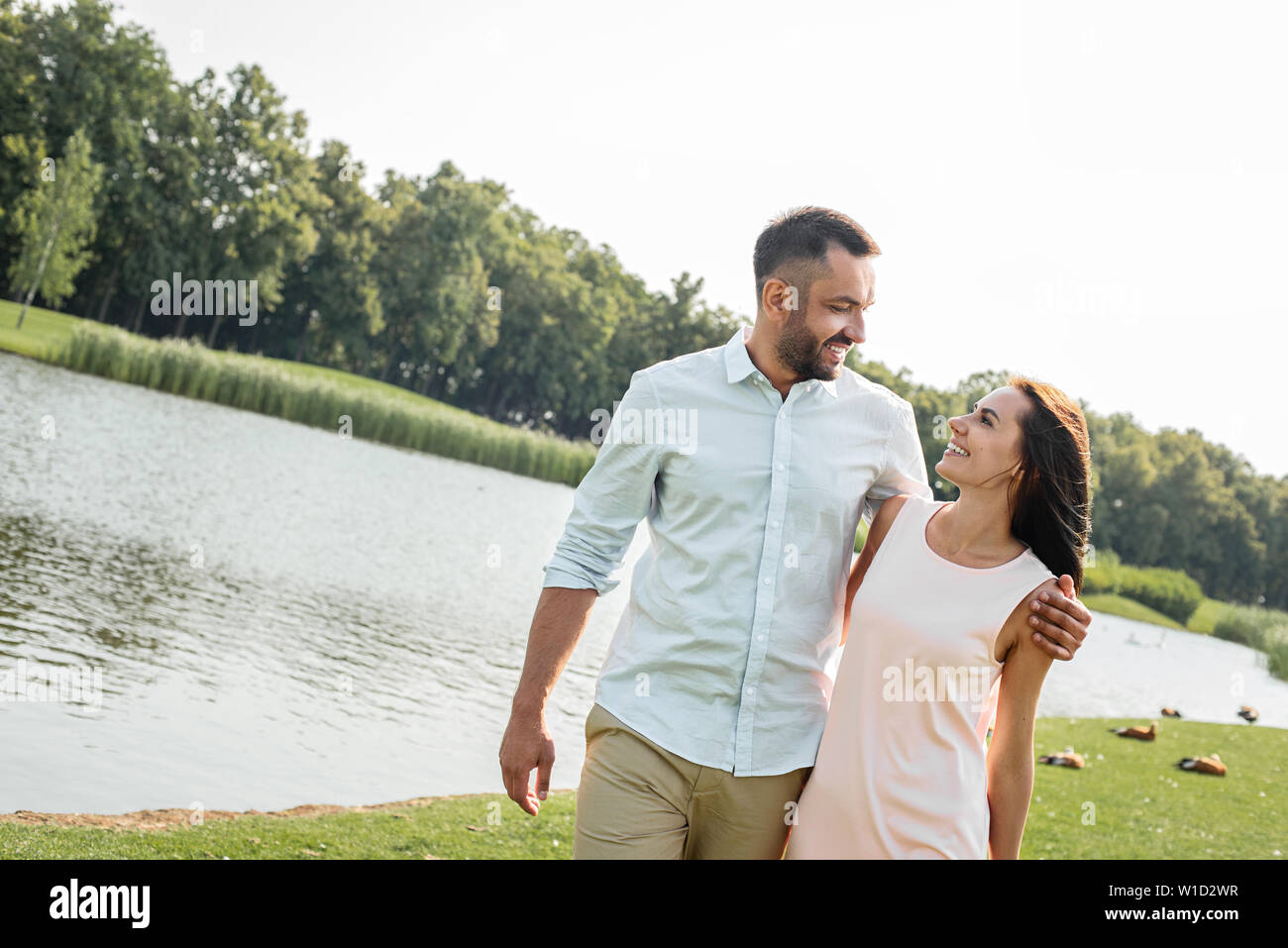 I love my wife Happy young couple smiling and looking at each other while walking outdoors near the river. Love and family concept. Love and family concept Stock Photo