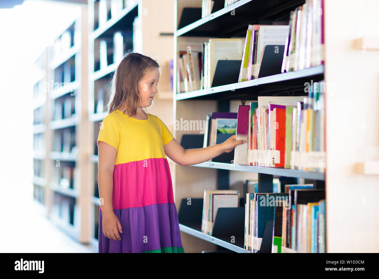 Child in school library. Kids read books. Little girl and boy reading and studying. Children at book store. Smart intelligent preschool kid choosing Stock Photo