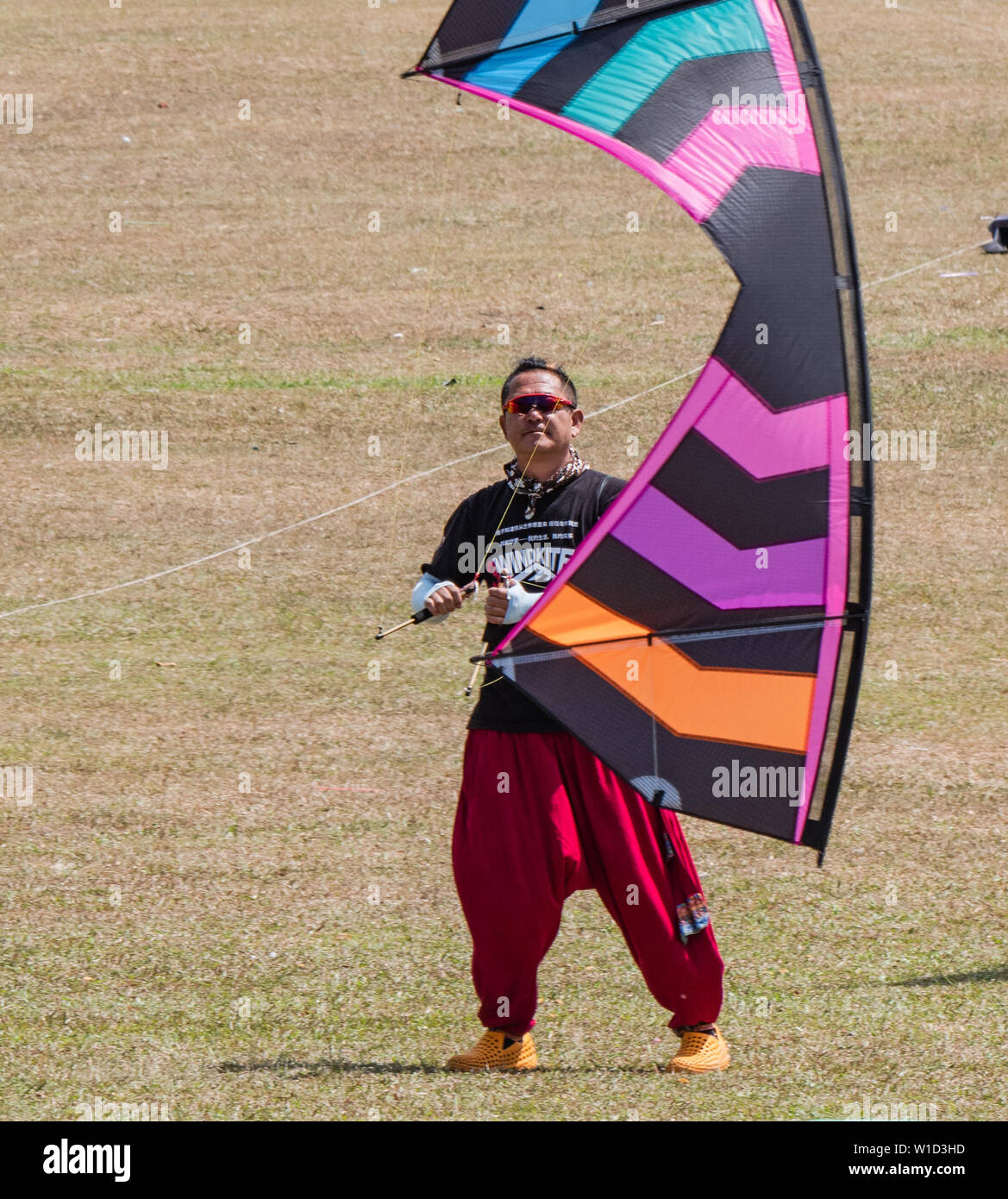 Pasir Gudang, Malaysia - March 3, 2019: Chinese kite flier Yao Qingshan flying a quad line kite on short lines at the 24th Pasir Gudang World Kite Fes Stock Photo