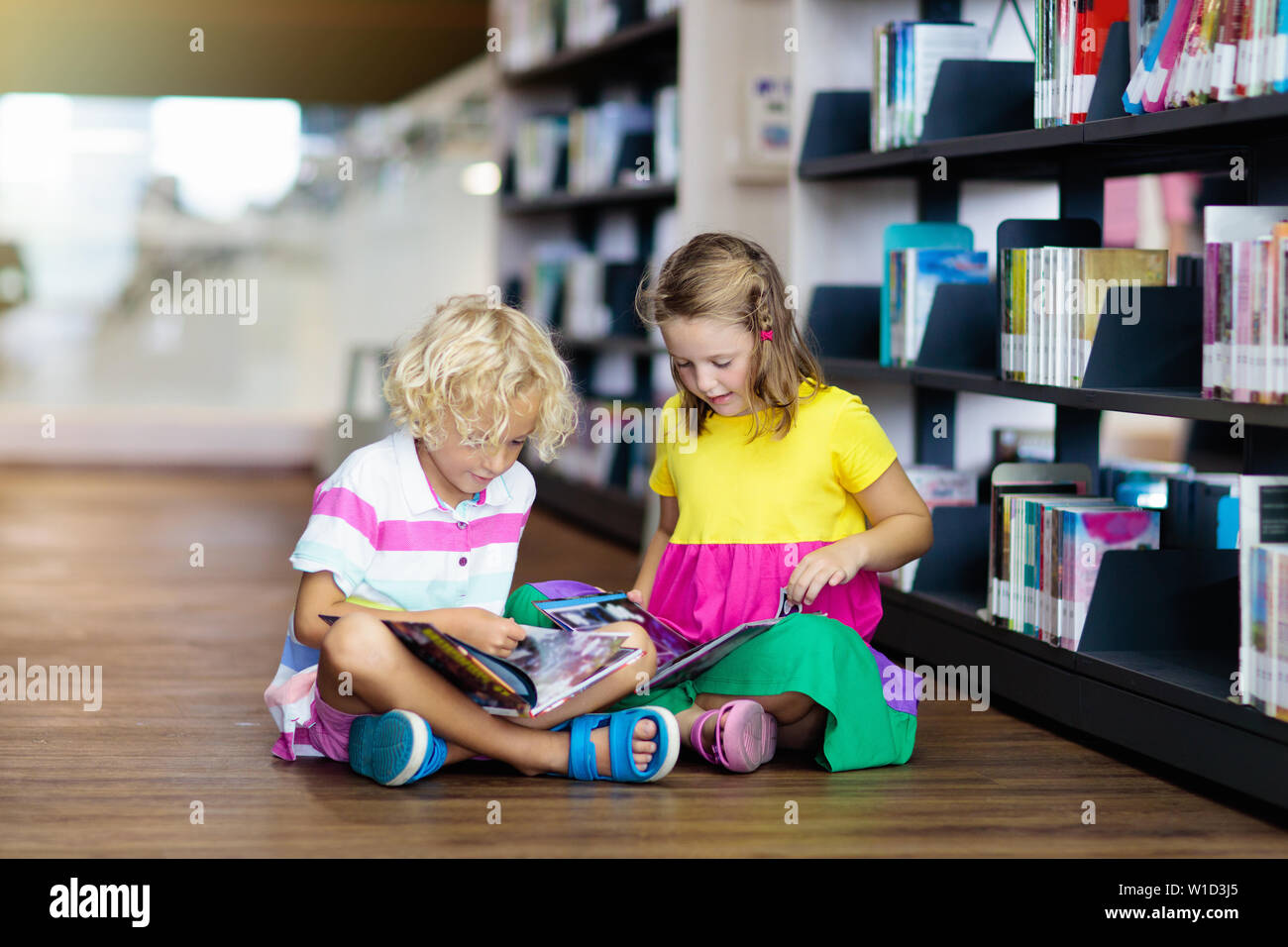 Child in school library. Kids read books. Little girl and boy reading and studying. Children at book store. Smart intelligent preschool kid choosing Stock Photo