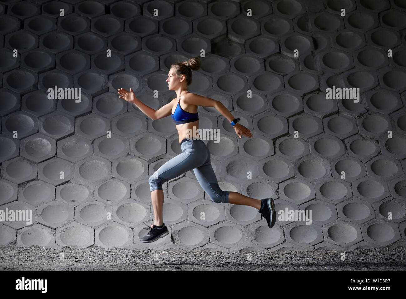 Side view of young athletic woman sprinting in urban setting Stock Photo