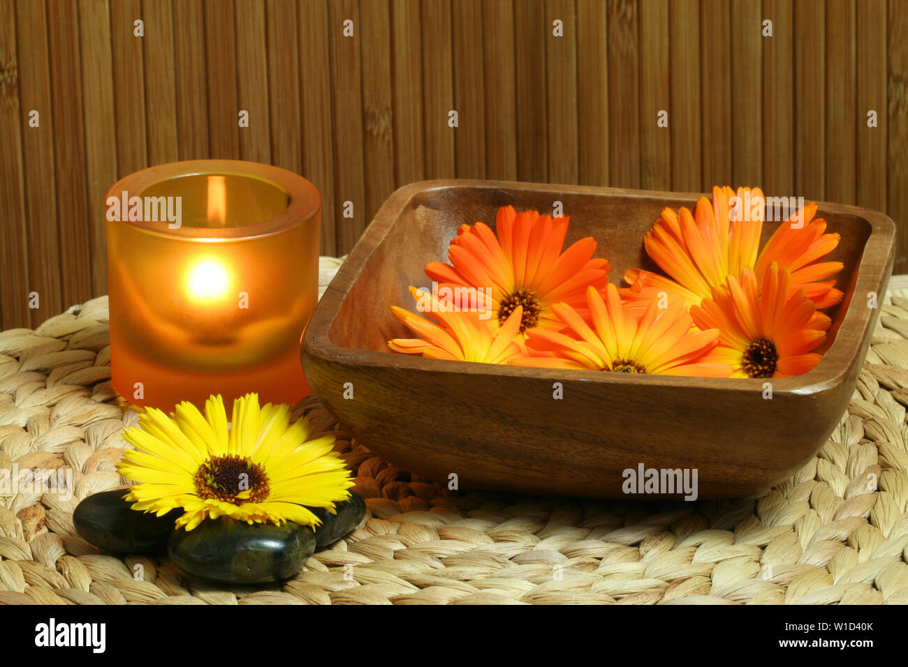 Beautiful natural spa composition. Marigold flowers in wooden bowl, zen stones and candle light Stock Photo