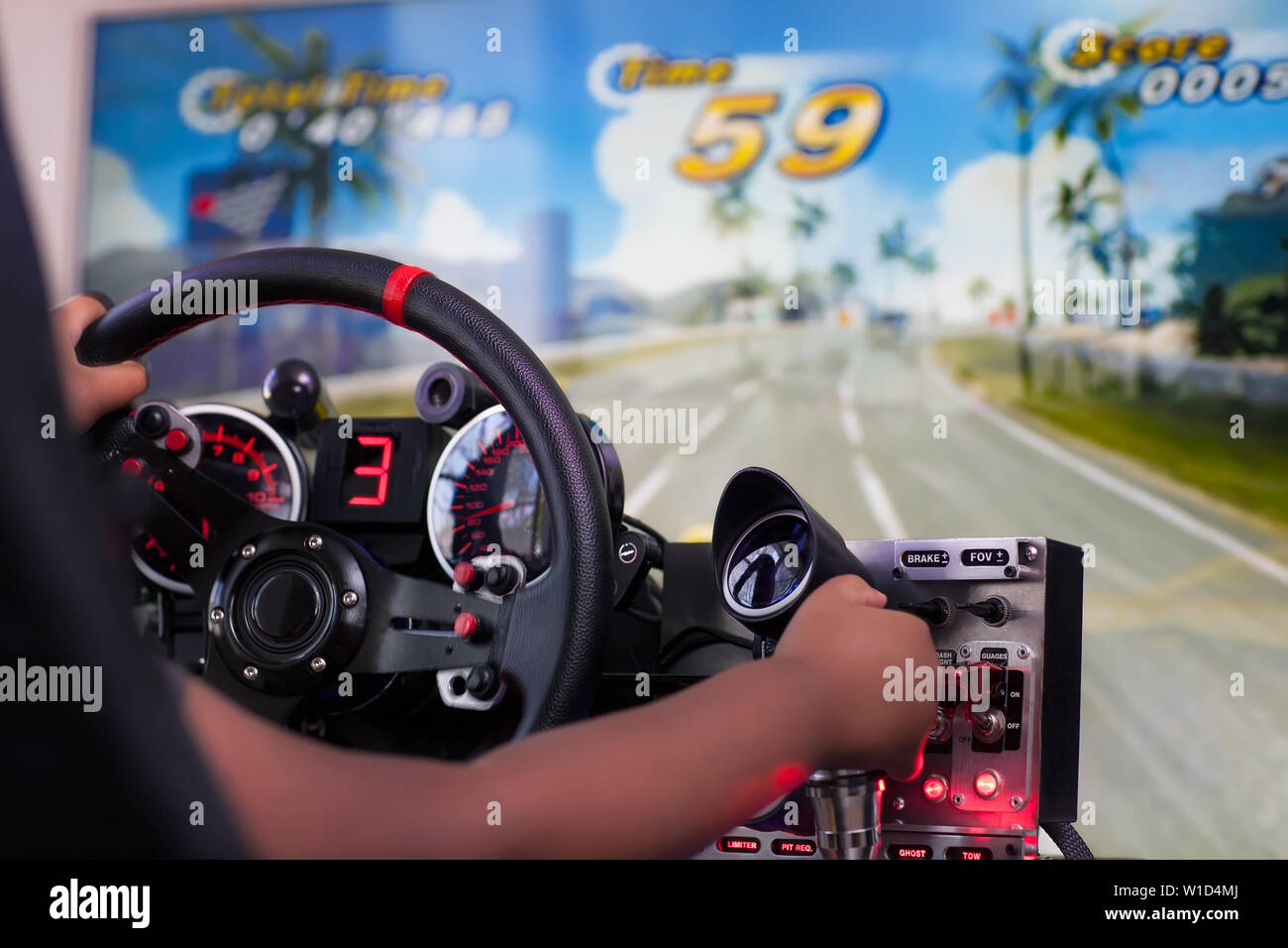 A kid playing an arcade style racing game and using the shifter knob from the simulator cockpit. Stock Photo
