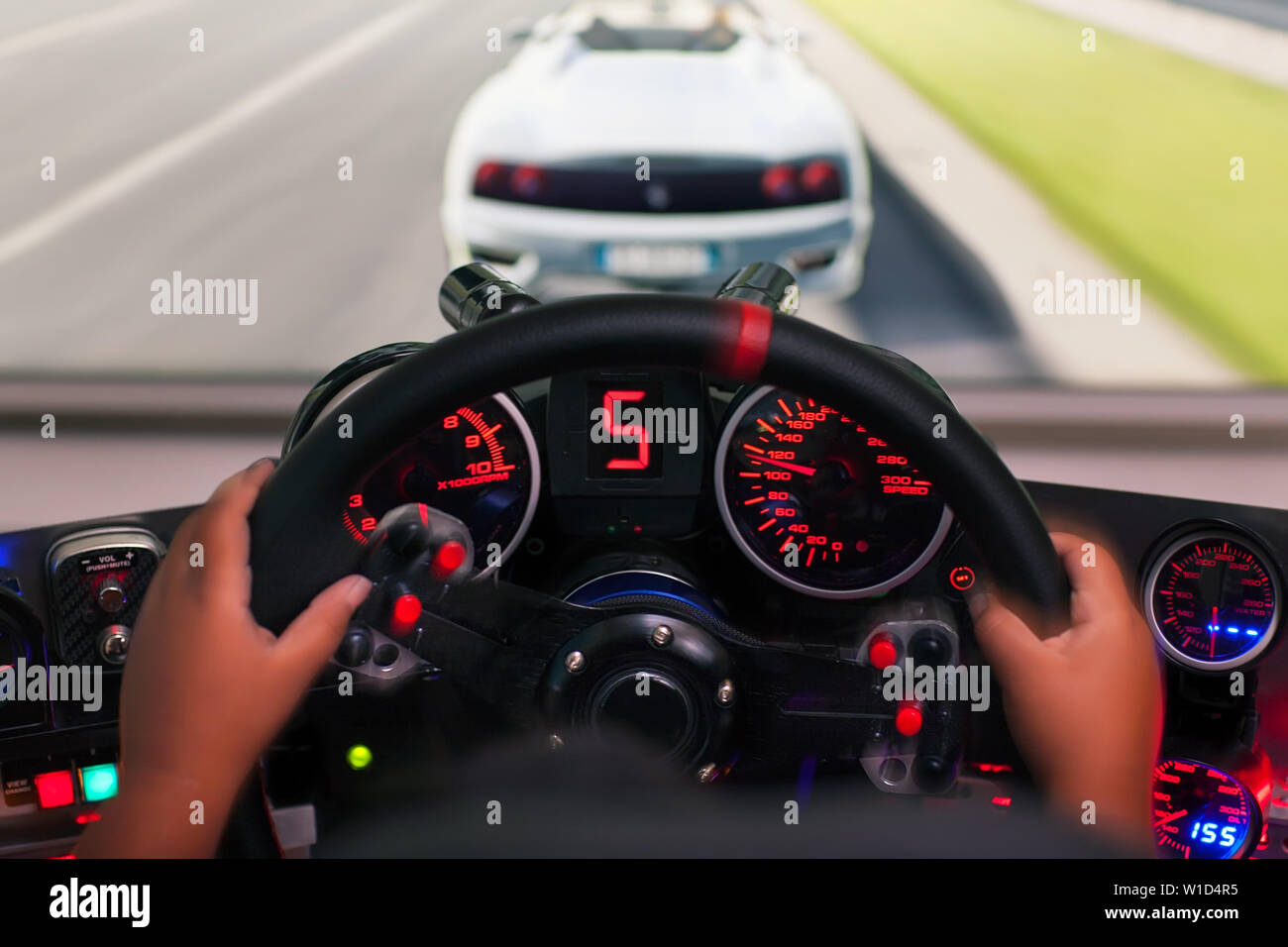 Hands of a kid on a steering wheel, while he plays a racing game in a