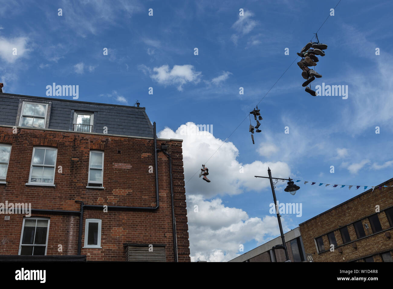 Shoefiti, the artistic expression of slinging shoes tied together by their laces over power lines, in Chapel Market, London, UK Stock Photo