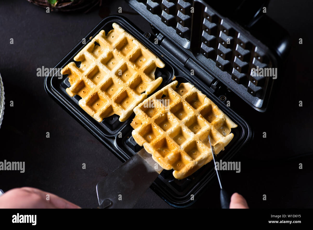 Waffles baking on a waffle maker close up Stock Photo