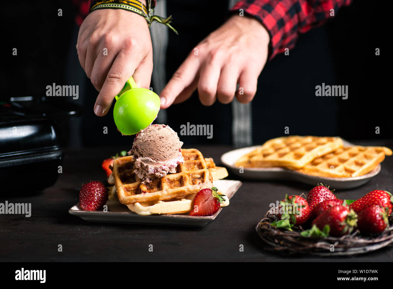 Chef adding ice cream on a waffle dessert close up Stock Photo