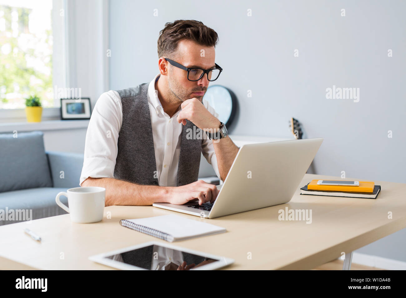 Pensive man working on laptop from home Stock Photo