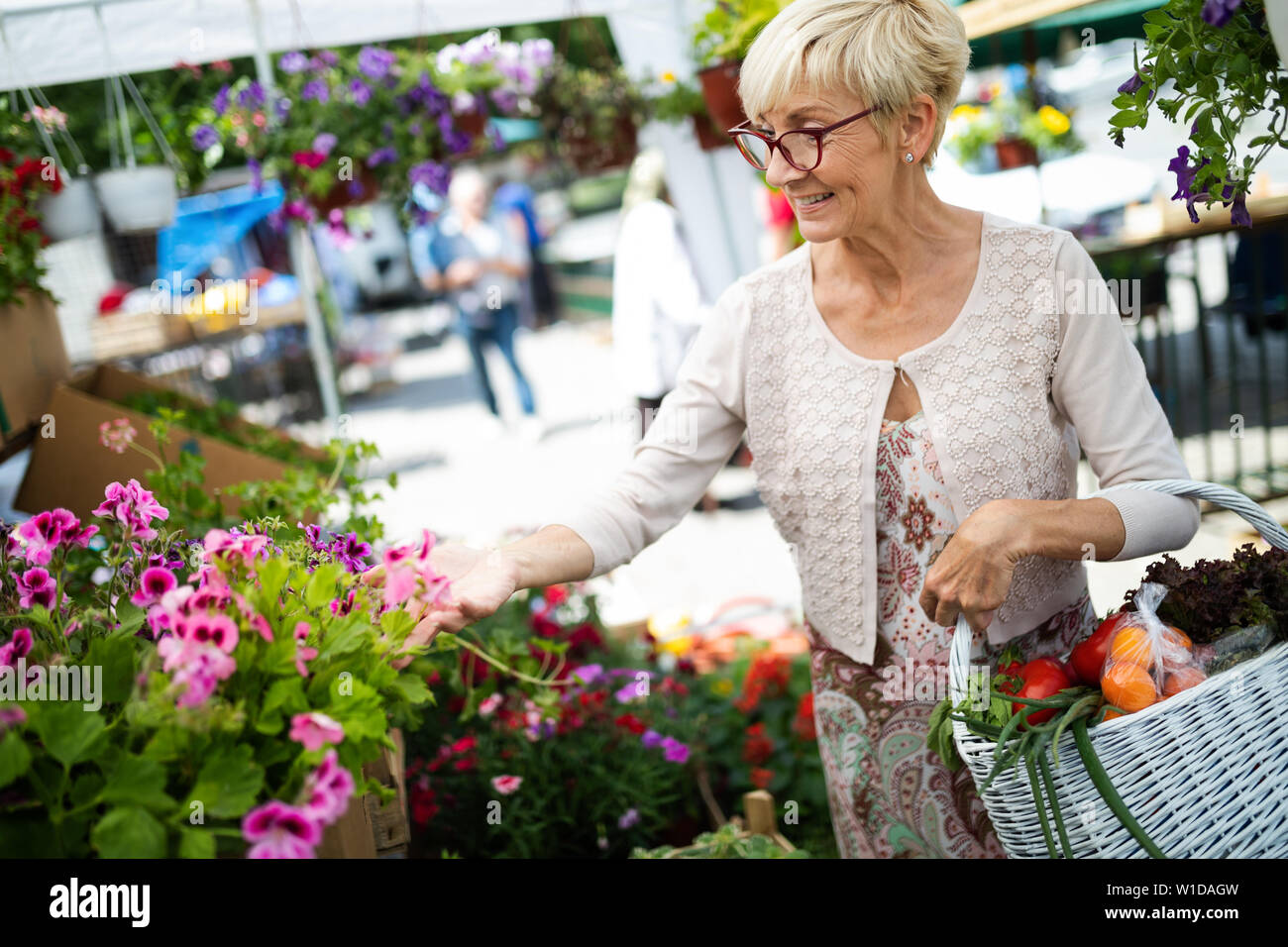 Senior lady shopping for flowers at garden center smiling Stock Photo
