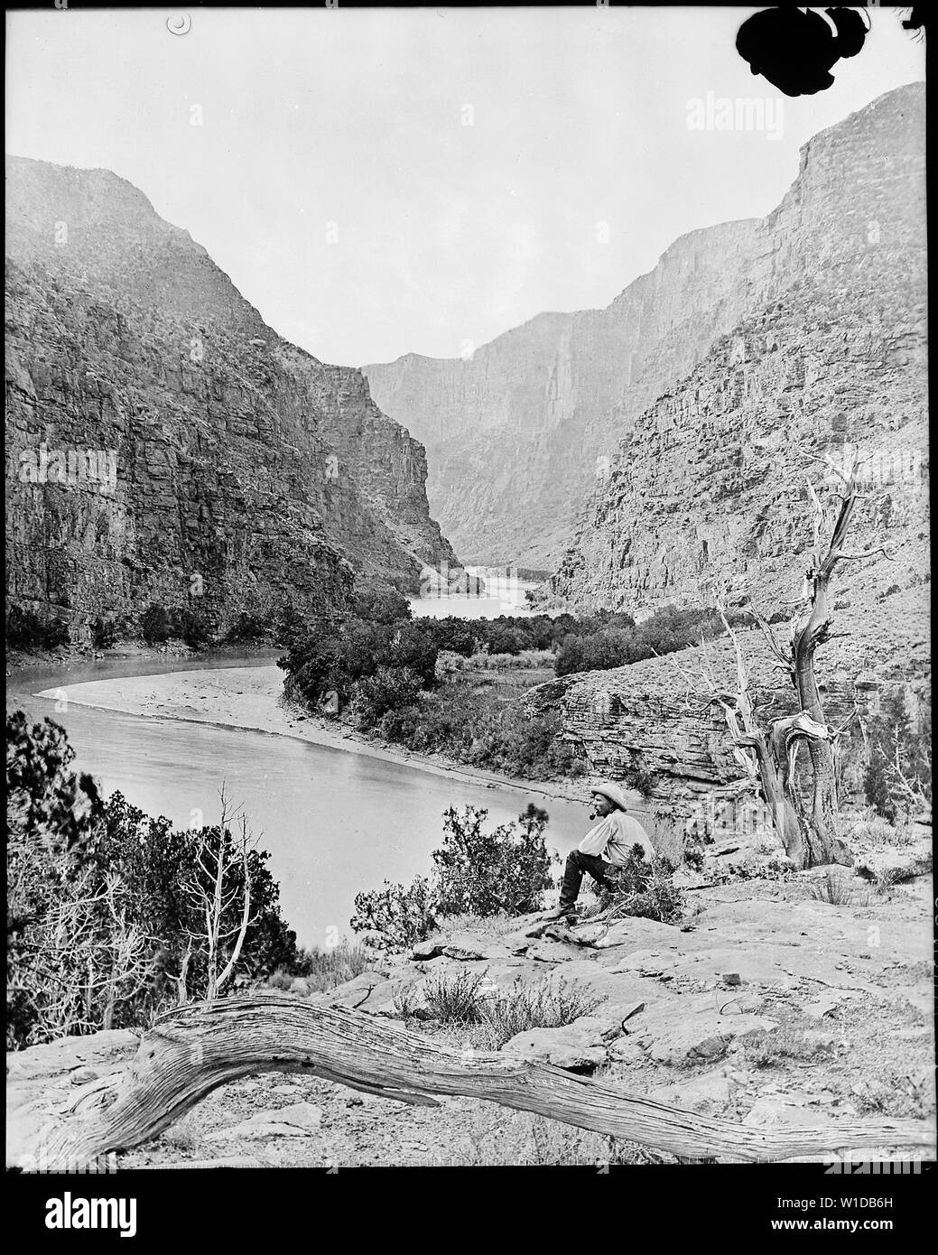 Gate of Lodore, Green River, N.W. Colorado? *James C. Pilling sitting peacefully on the bank smoking his pipe and wearing knee high leather boots., 1871 - 1878 Stock Photo