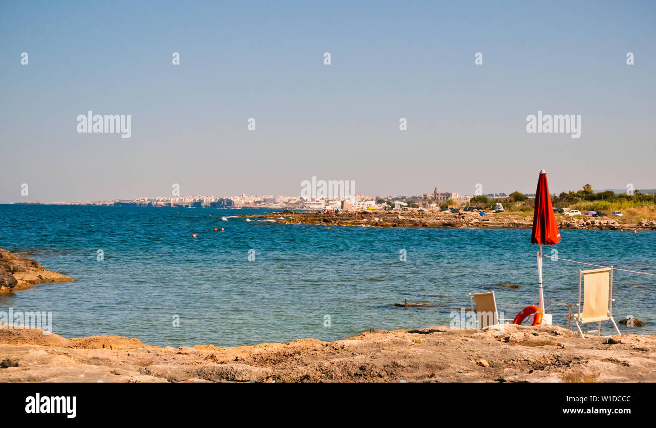 Beach on the Adriatic coast in the  background of the city of Polignano in the summer sunset . Stock Photo